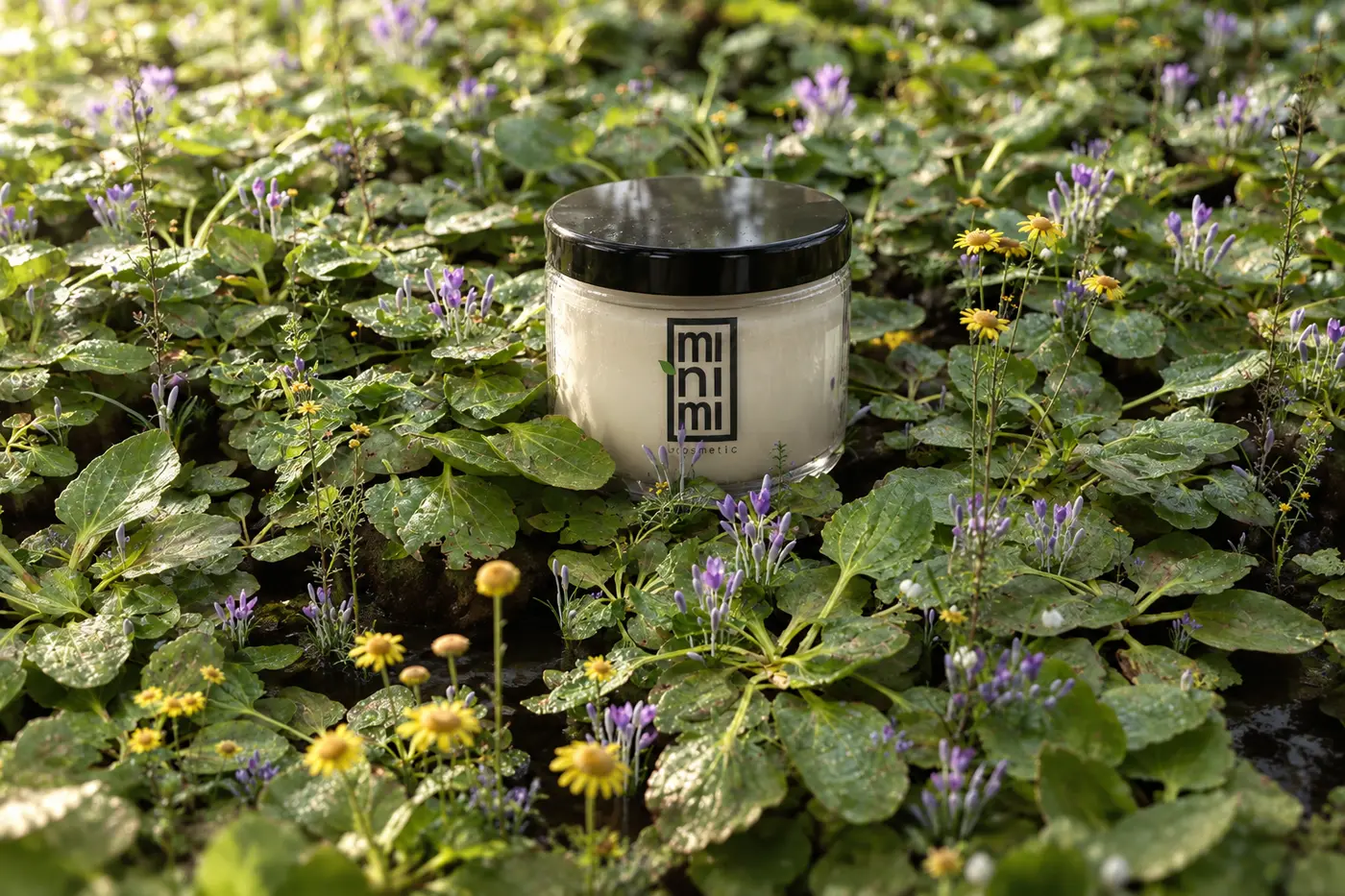 Pot Minini posé dans un parterre de fleurs