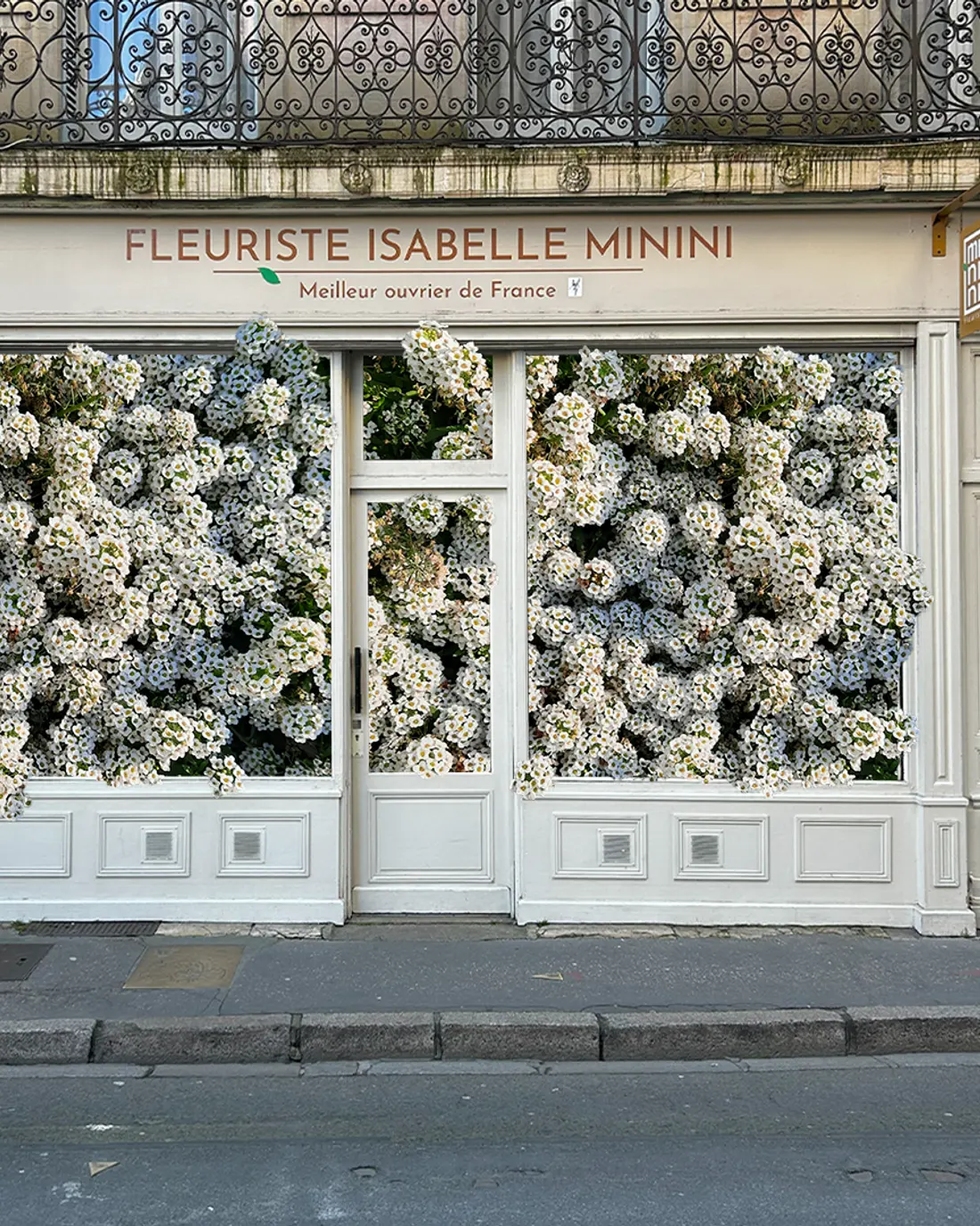 Vitrine de la boutique Isabelle Minini couverte de fleurs blanches