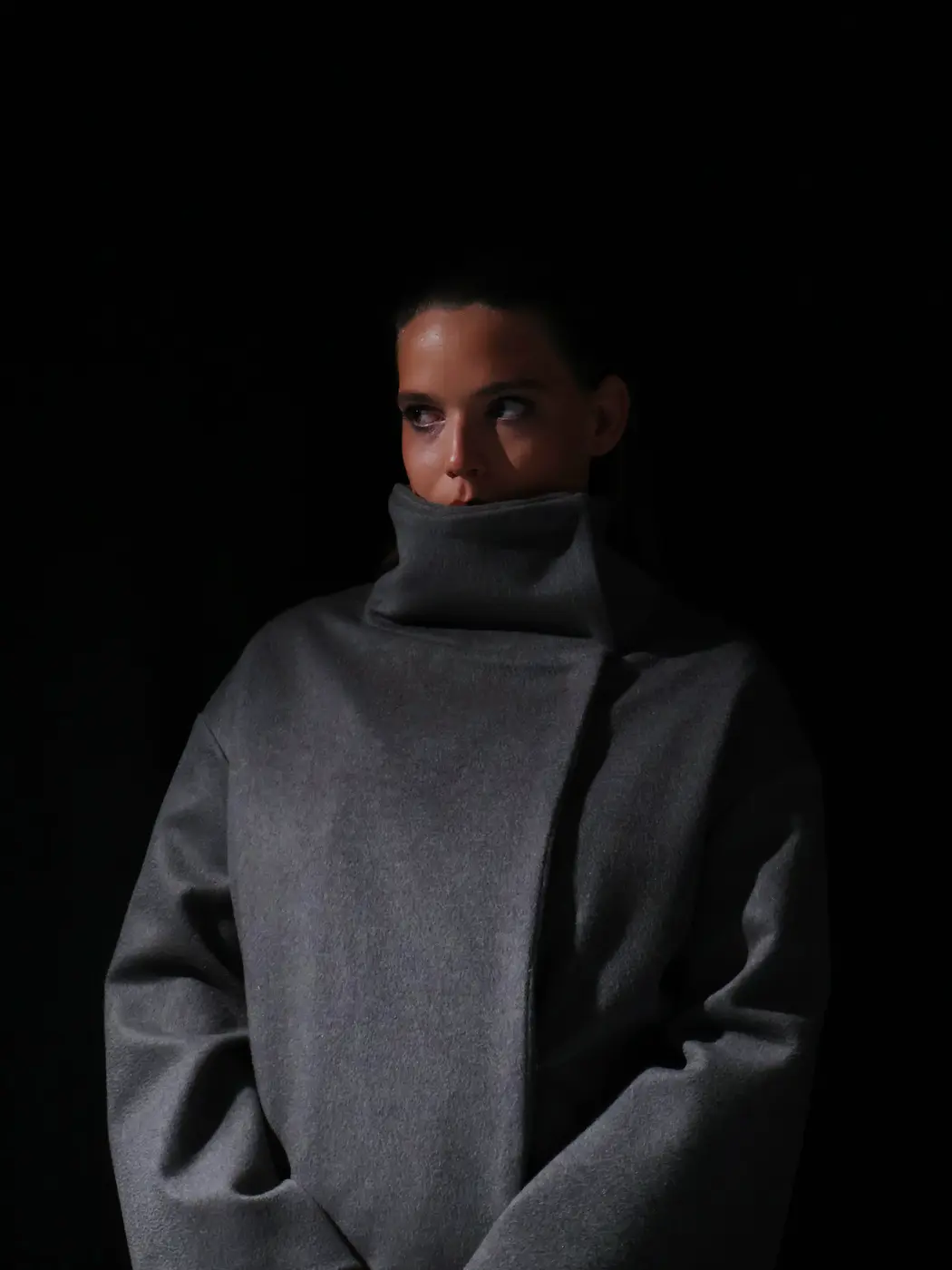 Manteau gris à col montant porté de face, sur fond noir