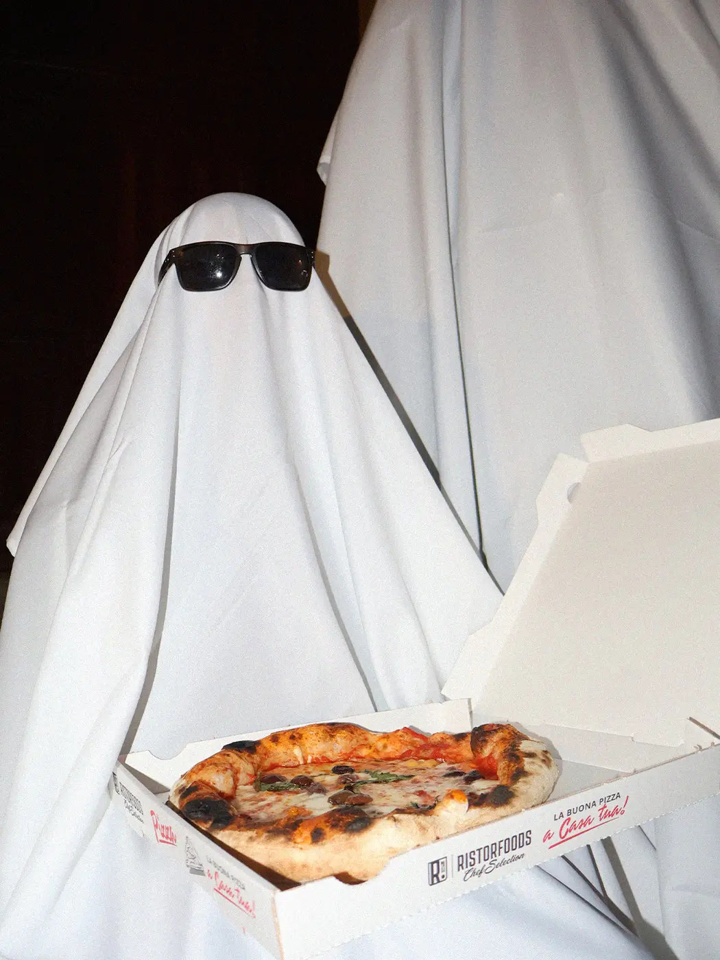 Personnage déguisé en fantôme tenant une pizza